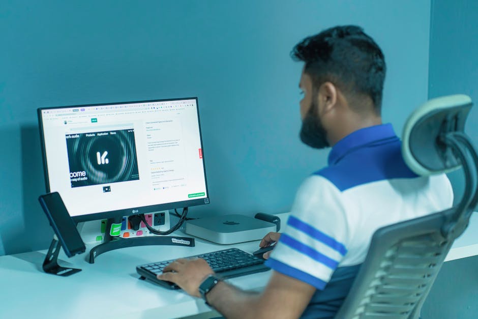 Man using a desktop computer with modern tech setup in a professional office environment.
